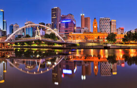 Melbourne CBD cityline at sunrise reflecting bright city illumination lights in still yarra river waters