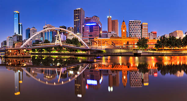 Melbourne CBD cityline at sunrise reflecting bright city illumination lights in still yarra river waters