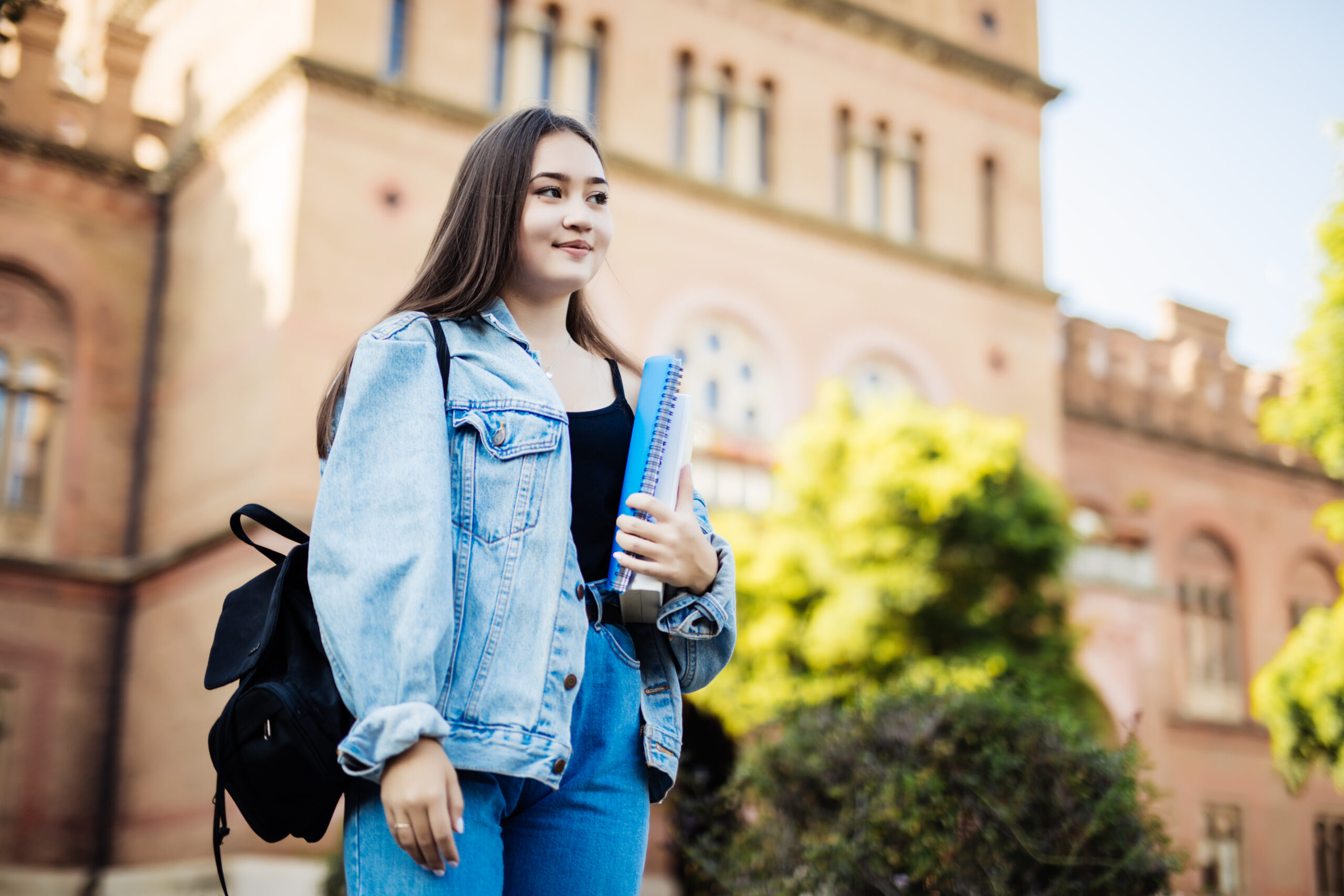 Student girl outside in summer park smiling happy. Asian female college or university student. Mixed race Asian woman model wearing school bag.